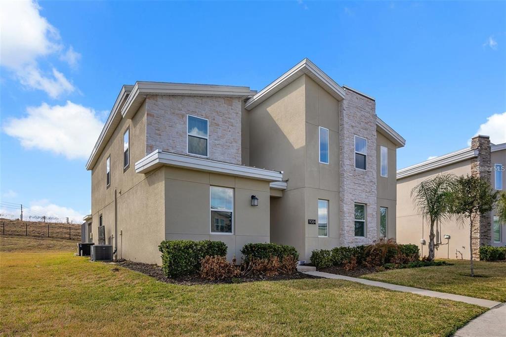A two-story house with tan stucco walls, stone accents, and a small front yard — 9084 SOMMERSET HILLS DRIVE, DAVENPORT, FL