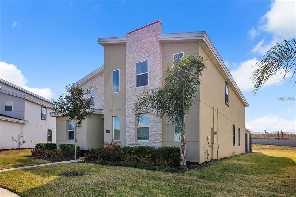 A two-story house with tan stucco walls, stone veneer accents, and a palm tree — 9084 SOMMERSET HILLS DRIVE, DAVENPORT, FL