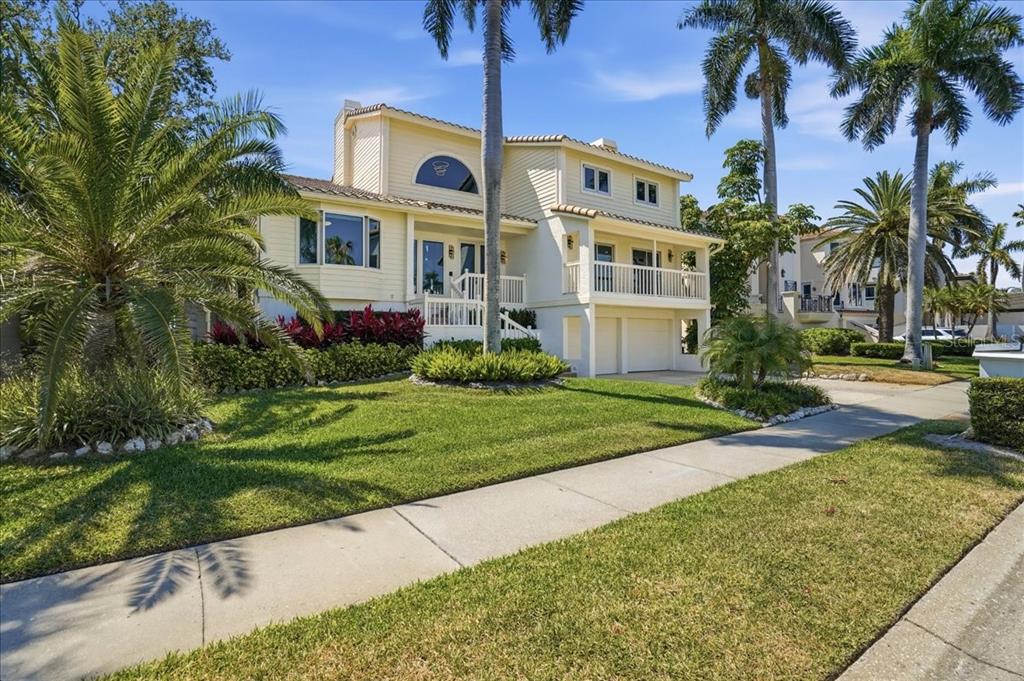 A two-story yellow house with a balcony, garage, and palm trees in the front yard — 3481 BAYOU SOUND, LONGBOAT KEY, FL
