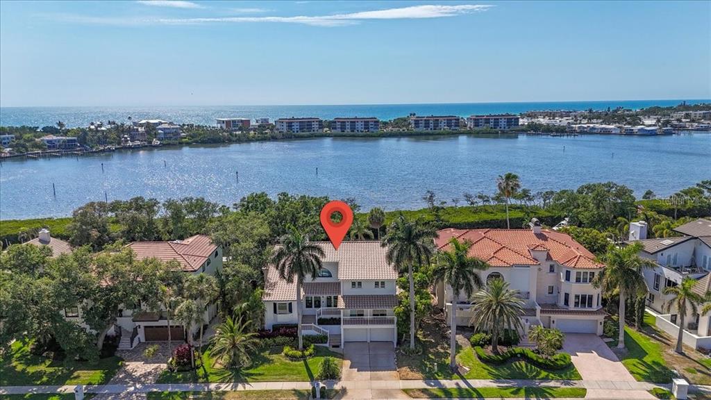 An aerial view shows a two-story house with a tile roof near a large bay — 3481 BAYOU SOUND, LONGBOAT KEY, FL