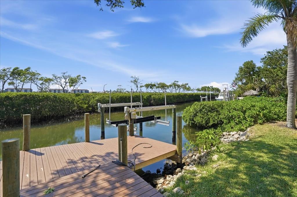 A wooden boat dock with a lift sits along a canal lined with mangroves — 3481 BAYOU SOUND, LONGBOAT KEY, FL