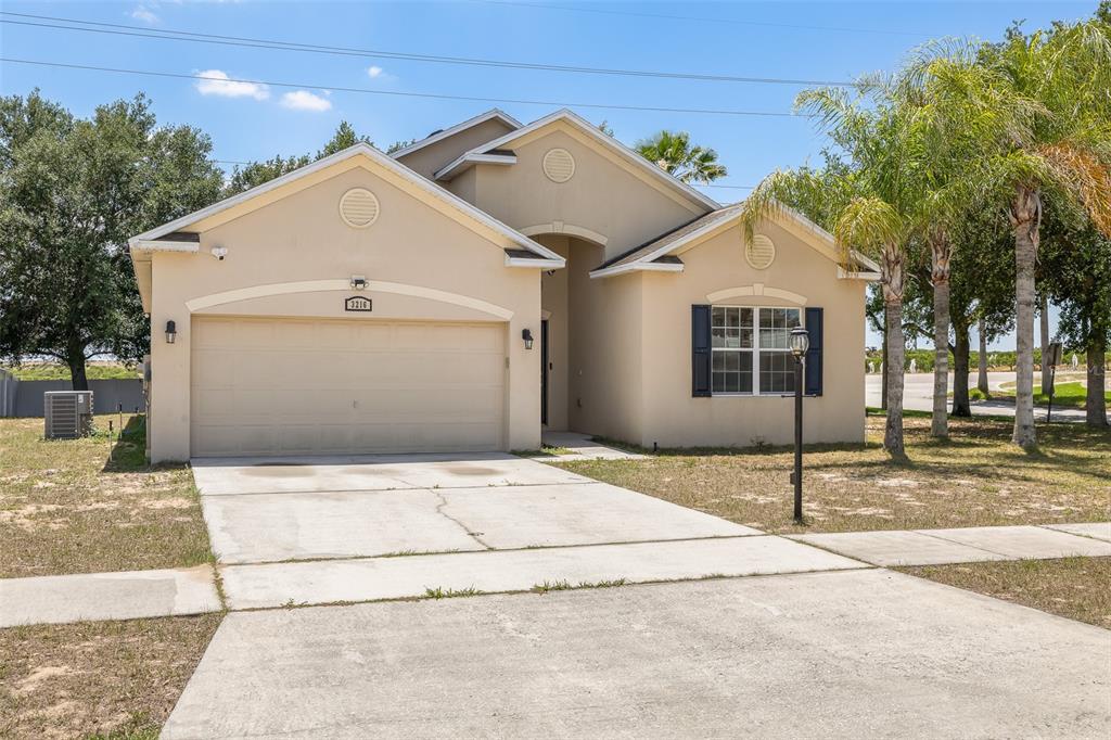 A single-story tan house with a two-car garage and a concrete driveway — 3216 LYNROCK AVENUE, DUNDEE, FL