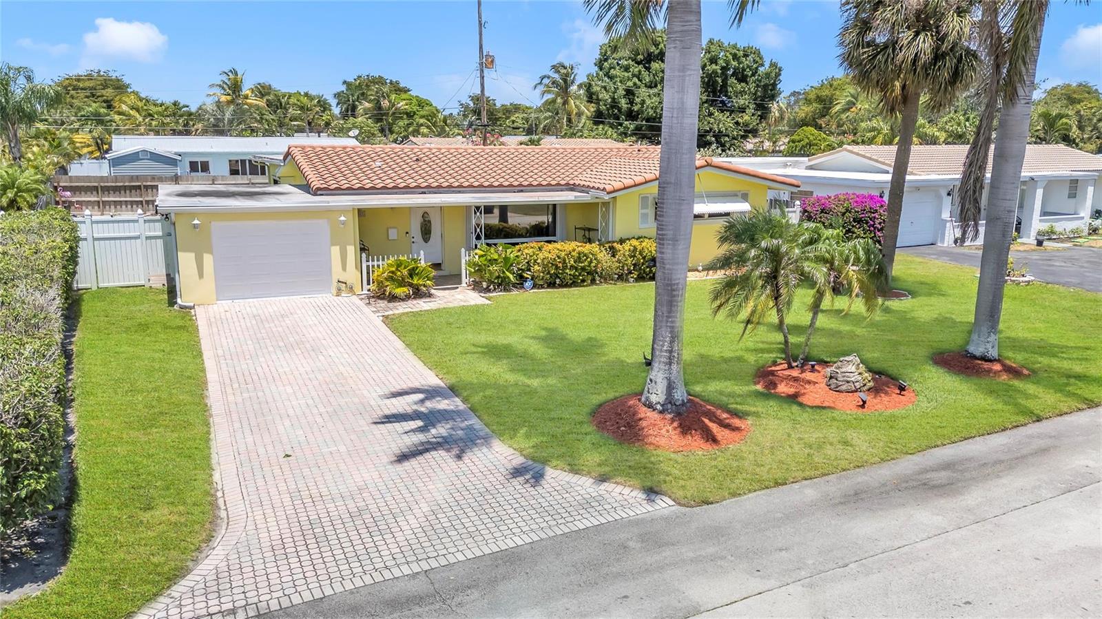 A yellow single-story house with a tile roof and a paved driveway sits on a lawn — 1961 NE 31ST Street, Lighthouse Point FL 33064, LIGHTHOUSE POINT, FL