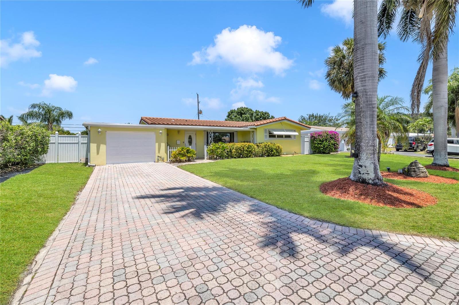 A yellow single-story house features a paved driveway, a garage, and palm trees — 1961 NE 31ST Street, Lighthouse Point FL 33064, LIGHTHOUSE POINT, FL