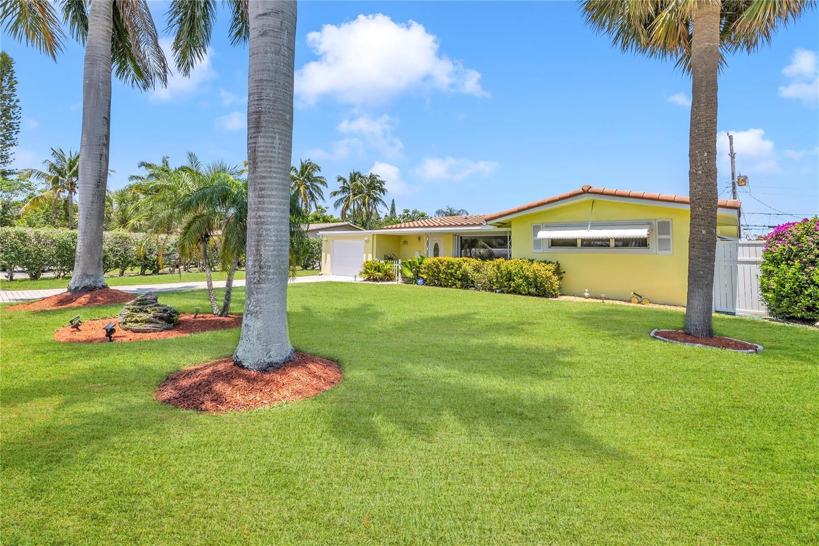 A yellow single-story house with a tile roof sits behind a large grassy lawn — 1961 NE 31ST Street, Lighthouse Point FL 33064, LIGHTHOUSE POINT, FL