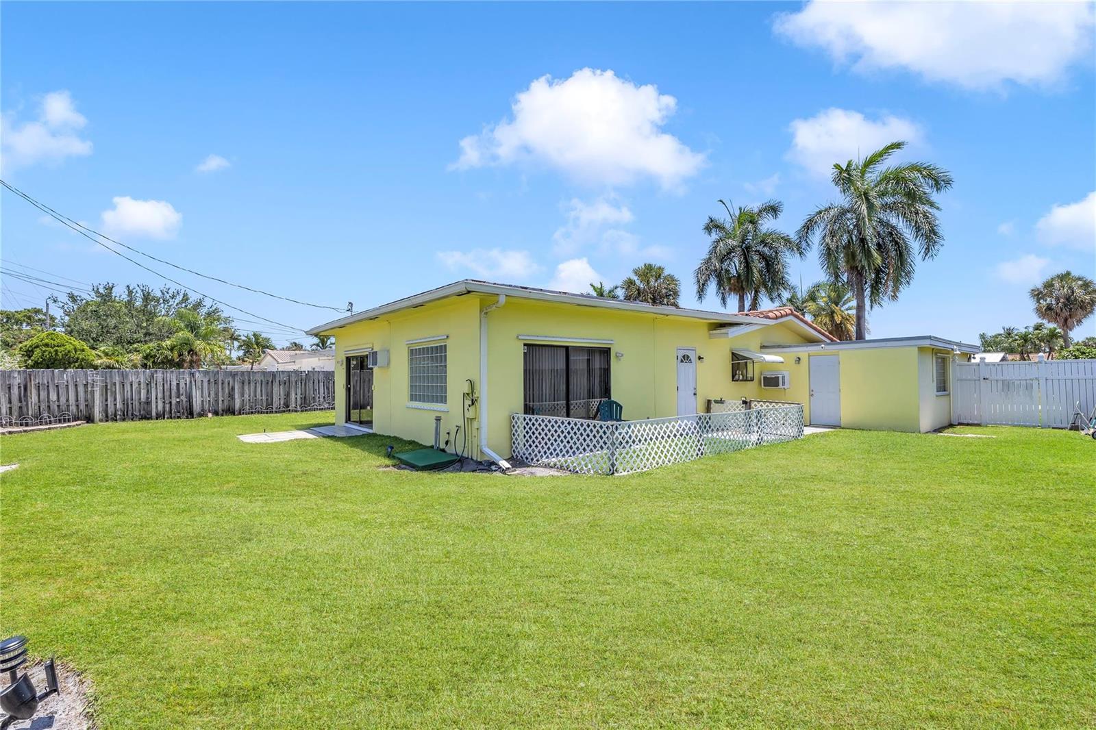 A yellow single-story house with a fenced backyard and palm trees under a blue sky — 1961 NE 31ST Street, Lighthouse Point FL 33064, LIGHTHOUSE POINT, FL
