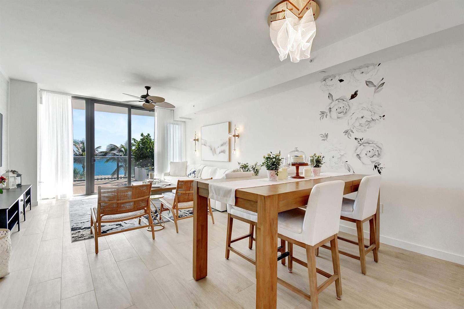 A bright living and dining area features light wood floors, a floral wall mural, and balcony — 1116 N Ocean Boulevard # 303, Pompano Beach FL 33062, POMPANO BEACH, FL