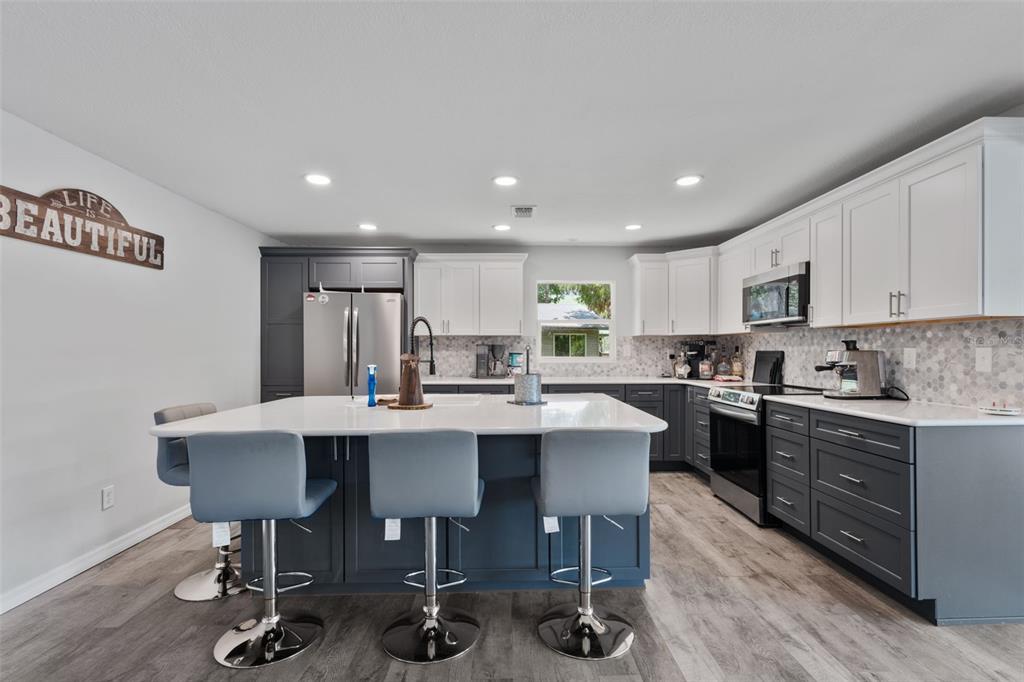A modern kitchen features a large island, two-tone cabinetry, and light-colored countertops — 15471 NW 46TH LANE, CHIEFLAND, FL