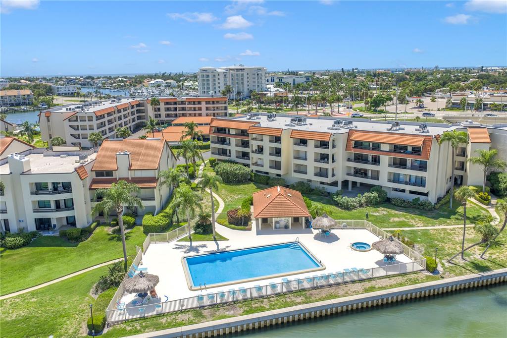 An aerial view of a multi-story apartment complex featuring a swimming pool and waterfront access — 103 1ST STREET E UNIT 313, ST PETERSBURG, FL