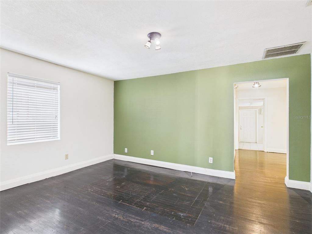 An empty room with yellow walls, dark wood flooring, a ceiling fan, and a window — 318 S 1ST STREET, LAKE WALES, FL