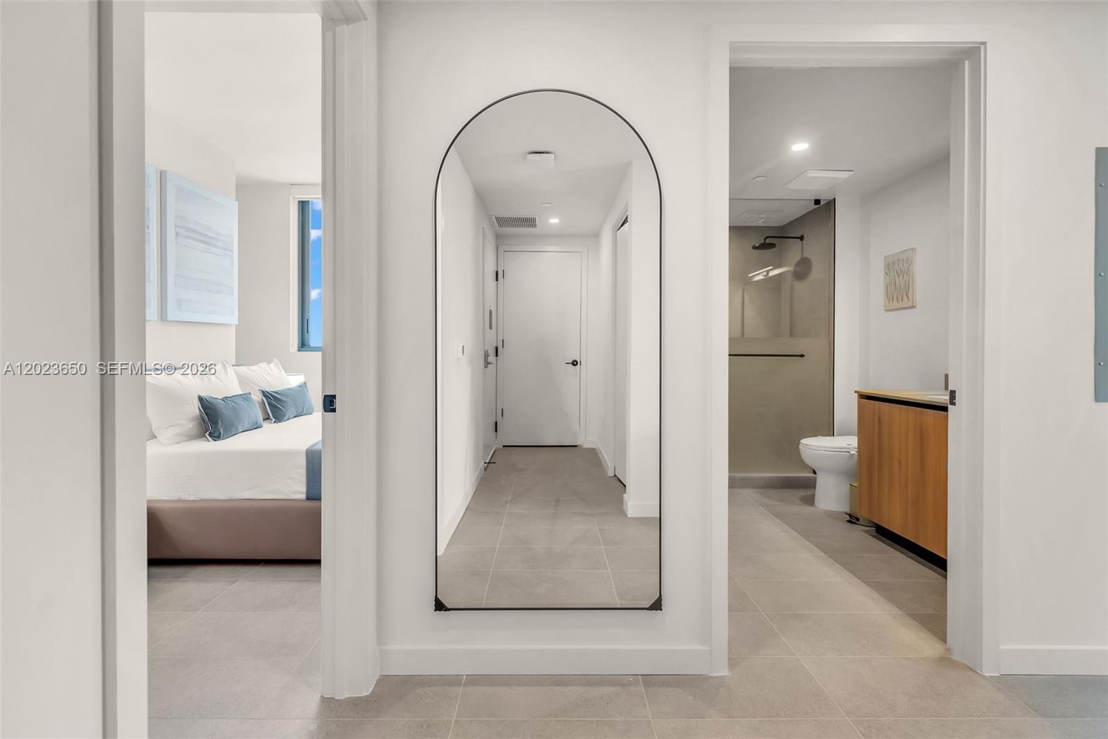 A hallway with a large arched mirror leads to a bedroom and a bathroom — 121 NE 5th St # 3401, Miami FL 33132, MIAMI, FL