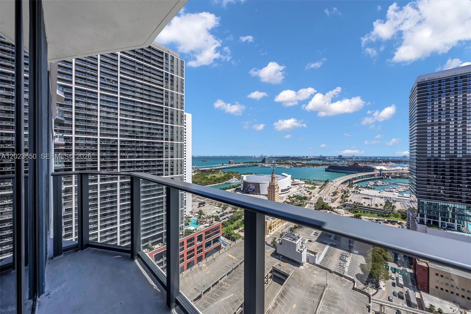 A high-rise balcony overlooks a city skyline, a stadium, and a bay with cruise ships — 121 NE 5th St # 3401, Miami FL 33132, MIAMI, FL