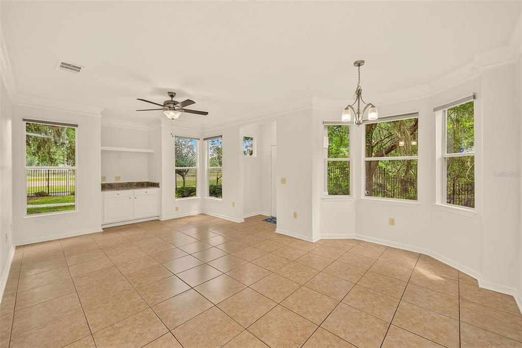 An open-concept room with tile flooring, a ceiling fan, a built-in cabinet, and large windows — 18138 VILLA CREEK DRIVE UNIT 18138, TAMPA, FL