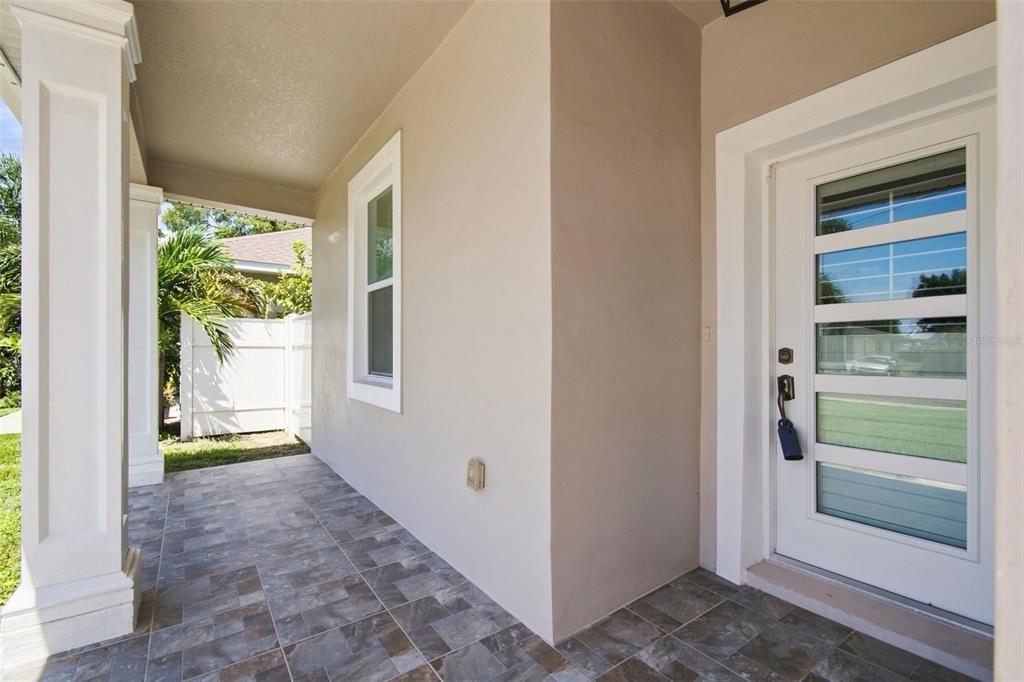 A covered front porch with tiled flooring leads to a white door with glass panels — 4011 55TH AVENUE N, ST PETERSBURG, FL