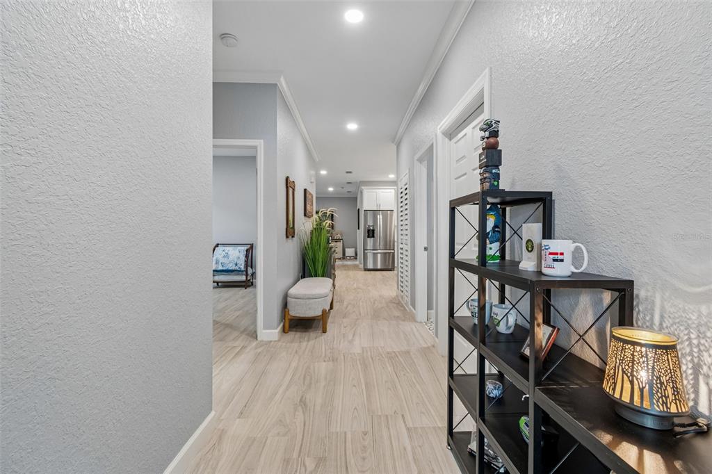 A hallway with light wood-look flooring leads toward a kitchen with stainless steel appliances — 4011 55TH AVENUE N, ST PETERSBURG, FL