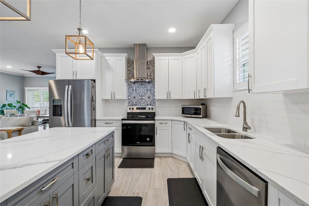 A modern kitchen features white cabinets, a gray island, stainless steel appliances, and patterned backsplash tile — 4011 55TH AVENUE N, ST PETERSBURG, FL