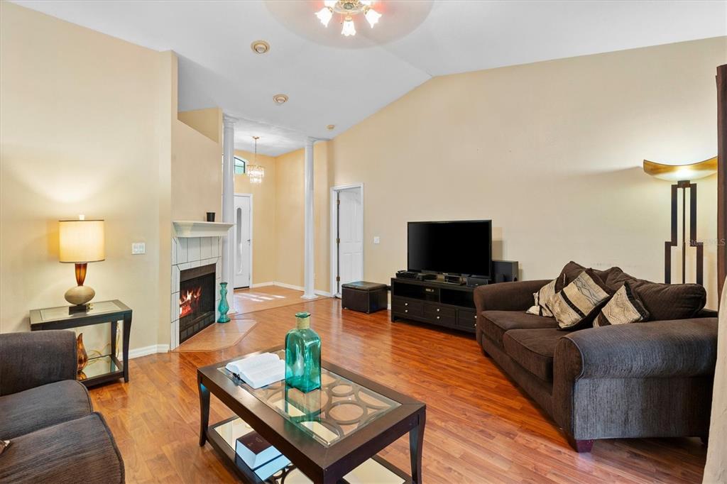 A living room features hardwood floors, a fireplace, a television console, and dark brown sofas — 7175 COUNTY ROAD 213, WILDWOOD, FL