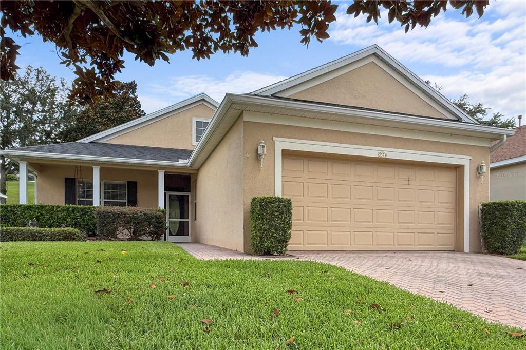 A single-story house with a beige stucco exterior, a two-car garage, and a paved driveway — 2371 CALEDONIAN STREET, CLERMONT, FL