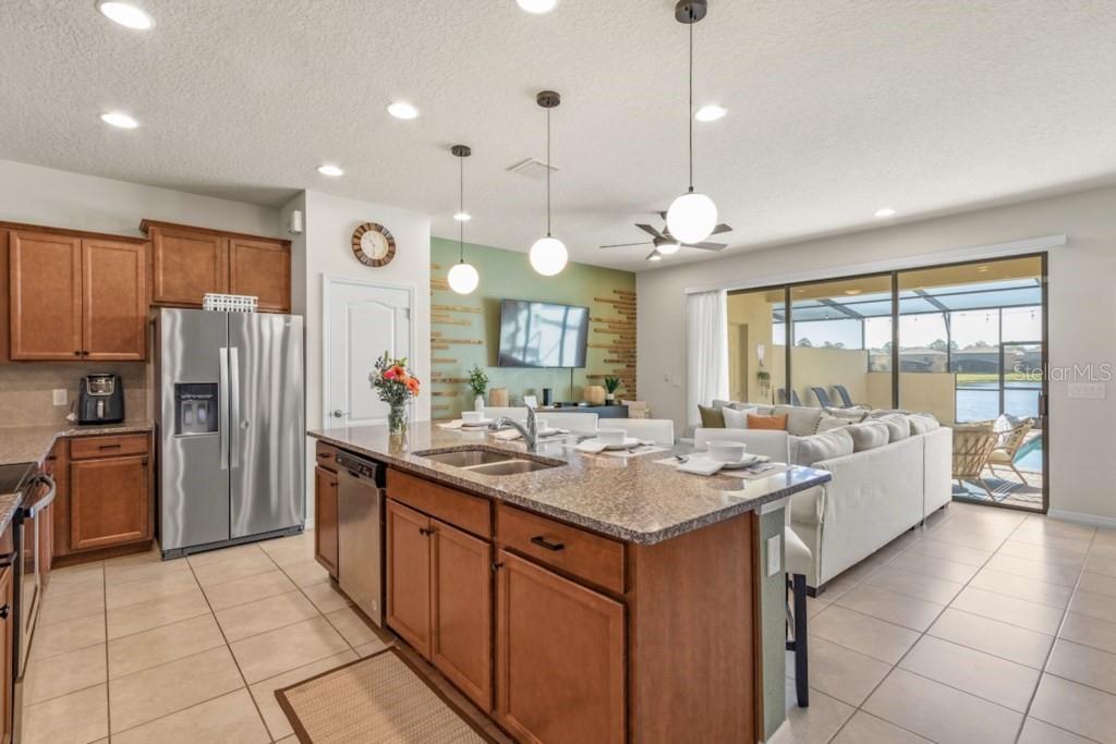 An open-concept living room and kitchen featuring a sectional sofa, dining area, and stairs — 8838 GENEVE COURT, KISSIMMEE, FL