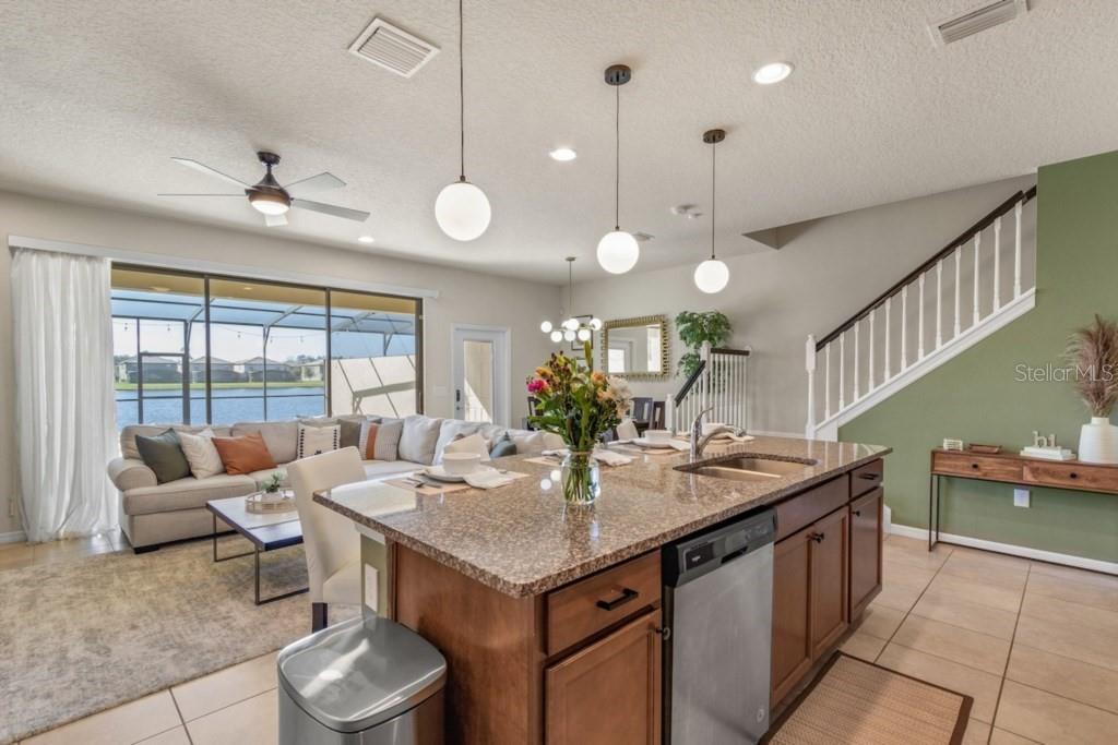 A kitchen with wood cabinets and granite countertops opens to a living area with views — 8838 GENEVE COURT, KISSIMMEE, FL