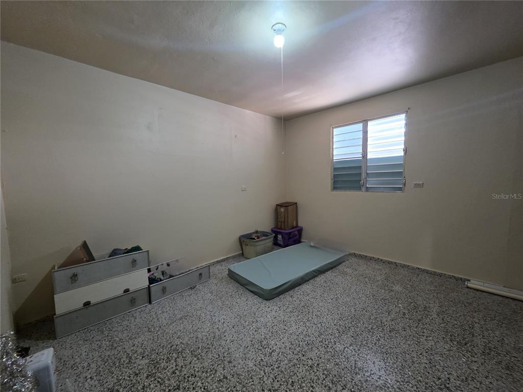 An empty bedroom features light-colored walls, a window with louvers, and a speckled tile floor — 638 km 3.5 BO ARRENALEJOS, ARECIBO, PR