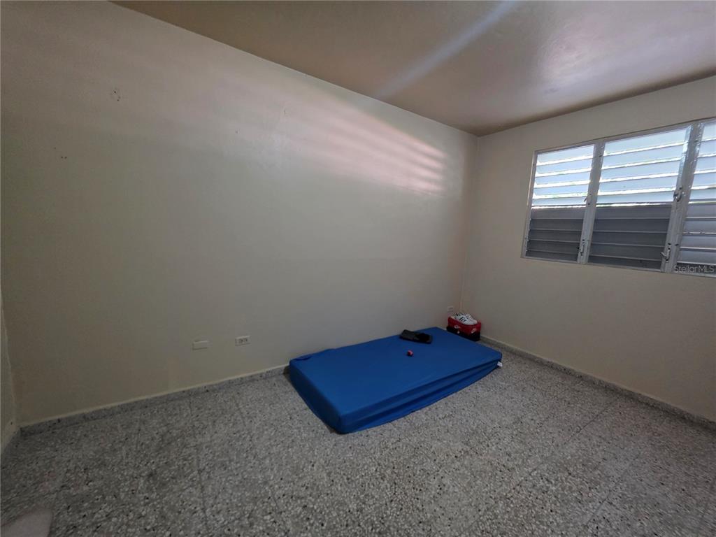 An empty bedroom features light-colored walls, a terrazzo floor, and a blue mattress on the floor — 638 km 3.5 BO ARRENALEJOS, ARECIBO, PR
