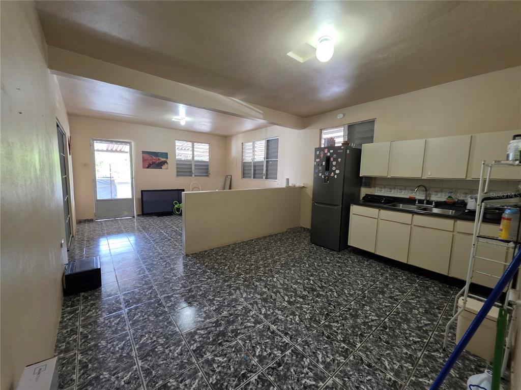 An open-concept kitchen and living area features dark patterned tile flooring and beige cabinetry — 638 km 3.5 BO ARRENALEJOS, ARECIBO, PR