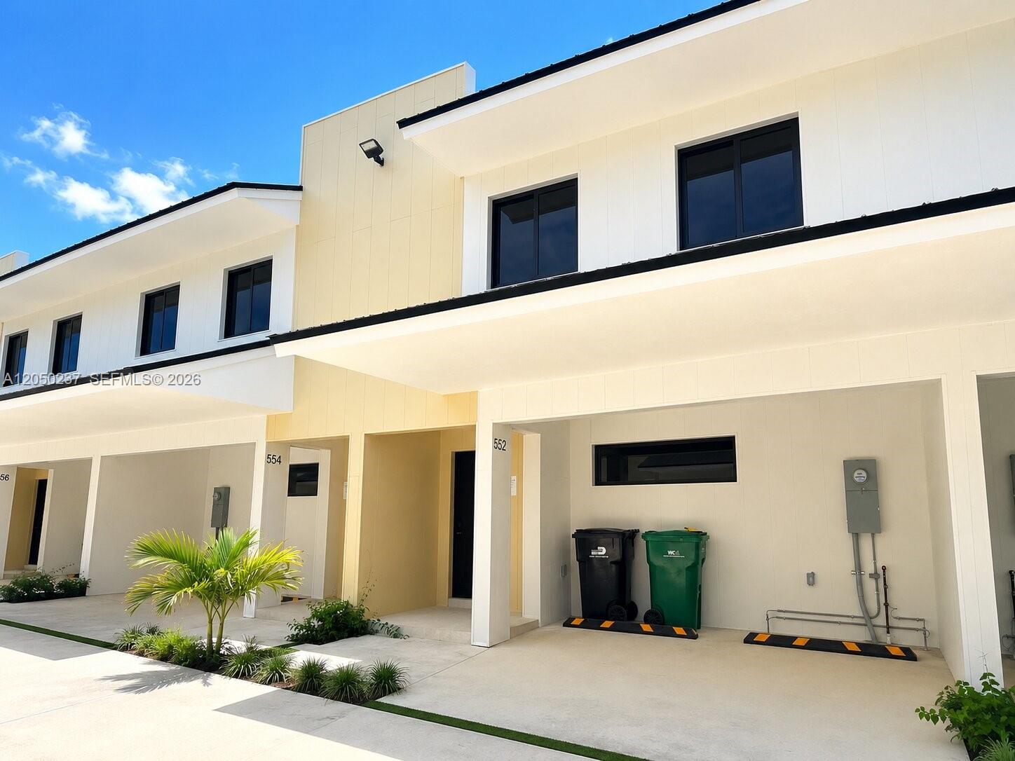 A row of modern two-story townhouses features white and yellow siding with covered carports — 552 NW 7th St # 6, Florida City FL 33034, FLORIDA CITY, FL