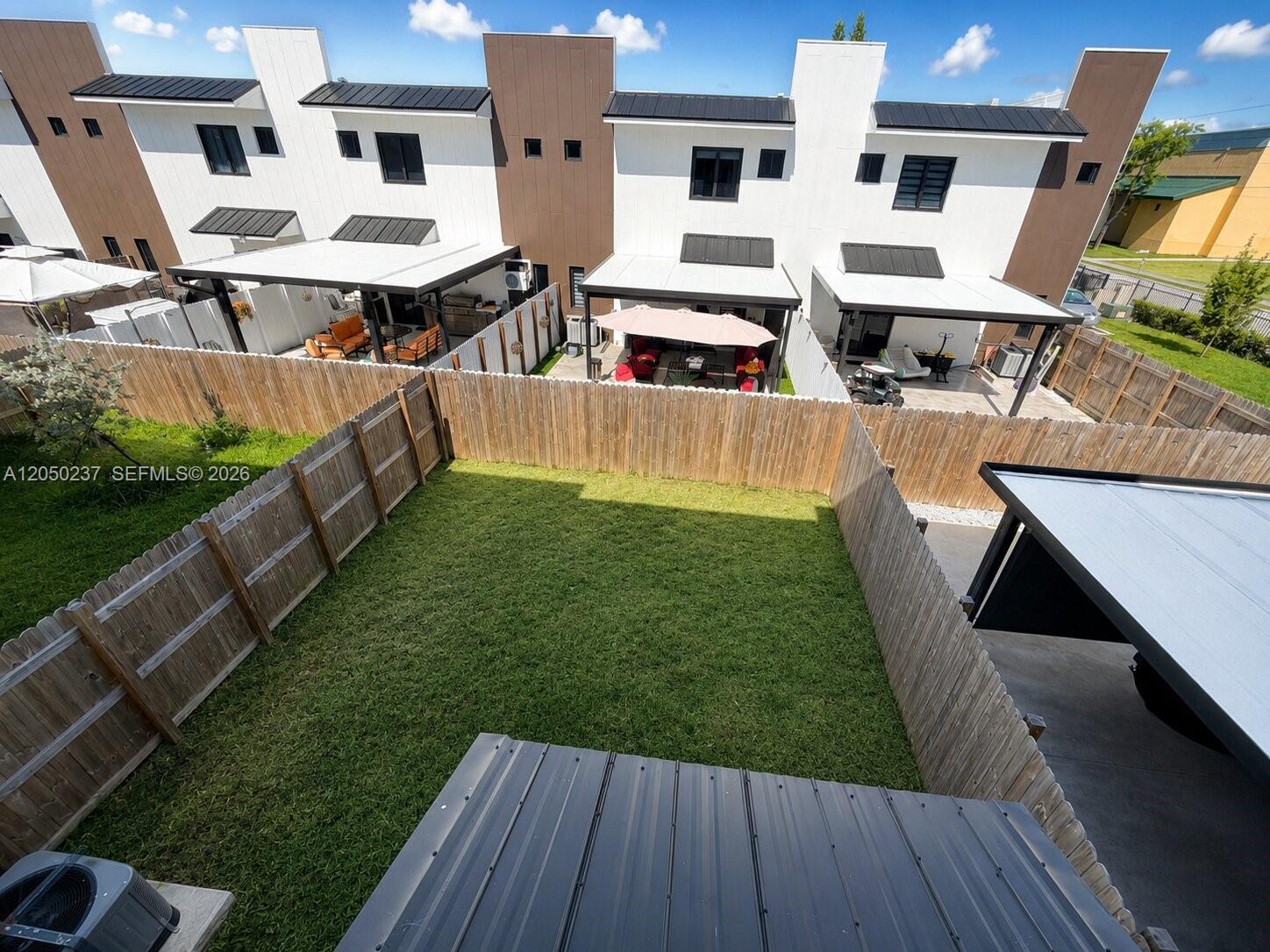 An elevated view shows a fenced backyard with a lawn between modern townhome patios — 552 NW 7th St # 6, Florida City FL 33034, FLORIDA CITY, FL