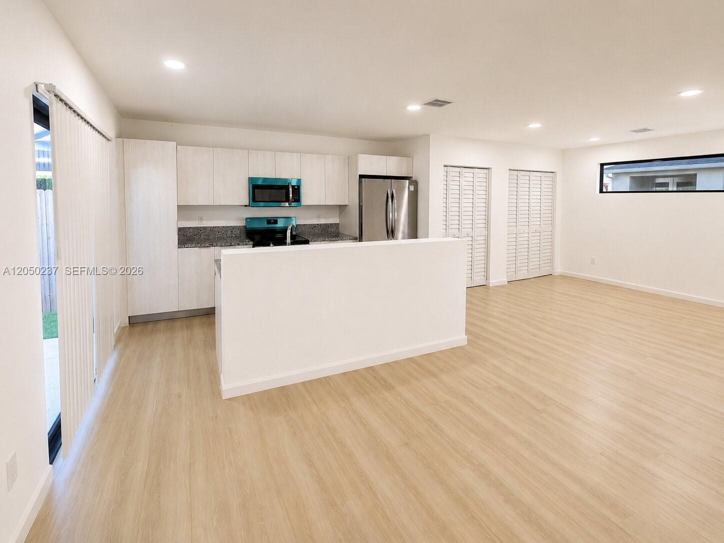 A kitchen with light wood cabinets and stainless steel appliances overlooks an open living area — 552 NW 7th St # 6, Florida City FL 33034, FLORIDA CITY, FL