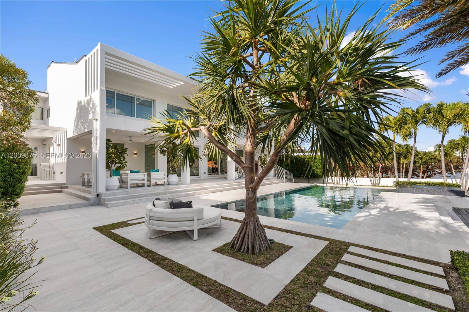 A modern white house features a swimming pool, a circular outdoor sofa, and a palm tree — 120 Knollwood Dr, Key Biscayne FL 33149, KEY BISCAYNE, FL