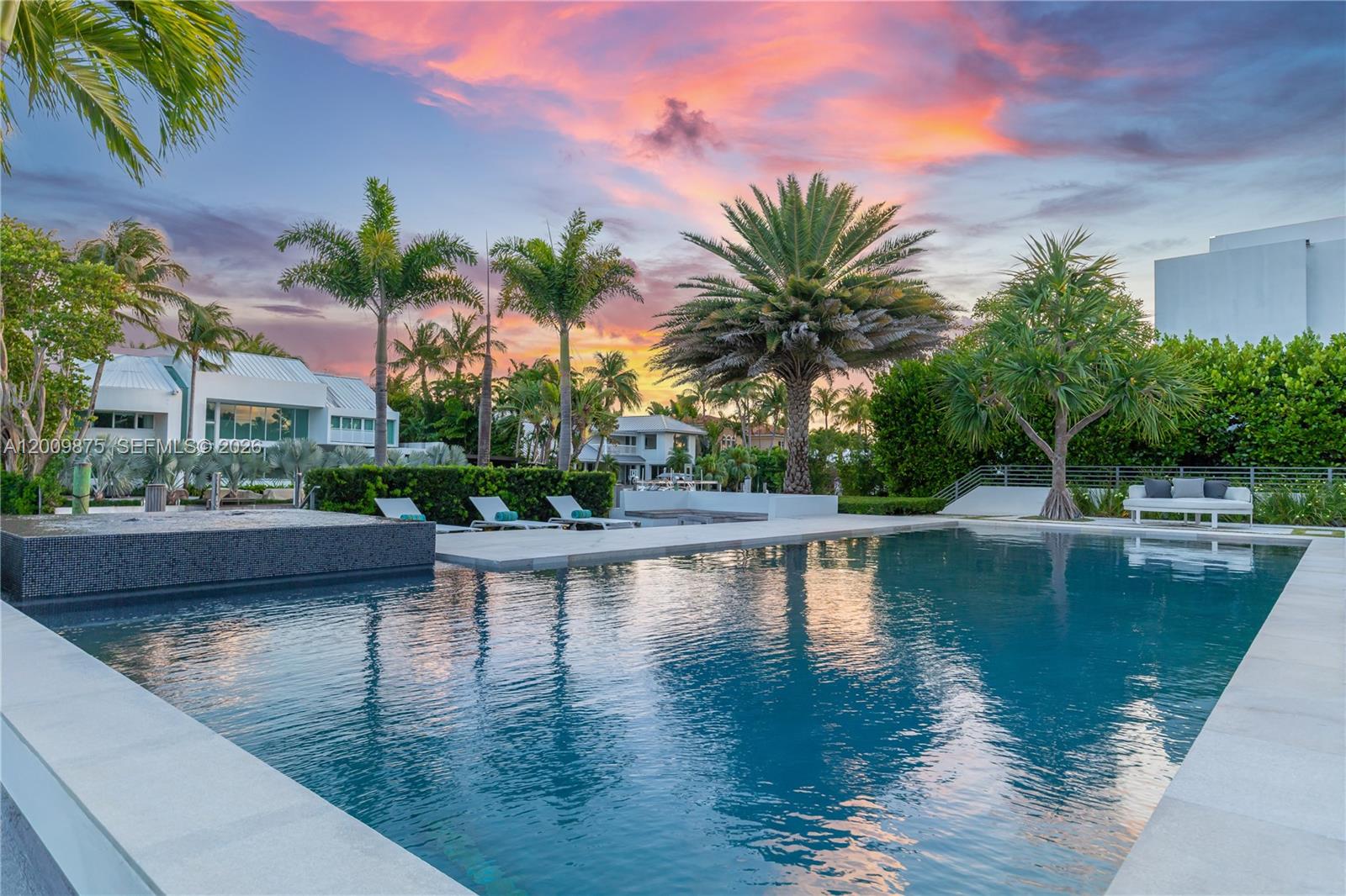 A swimming pool with a tiled edge sits in front of a modern house exterior — 120 Knollwood Dr, Key Biscayne FL 33149, KEY BISCAYNE, FL