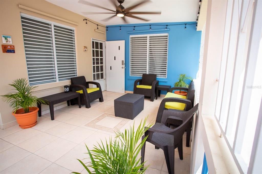 A covered patio features tiled floors, dark wicker furniture, and a blue accent wall — 373 CALLE FRANCISCO COLON GUERRA BO PUEBLO, RINCON, PR