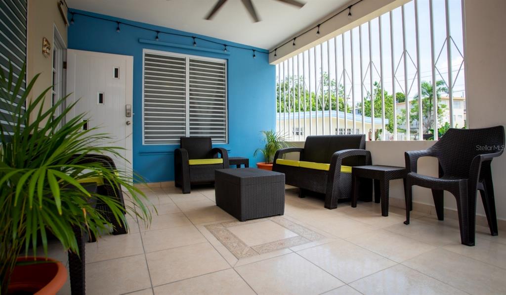 A covered patio features tiled floors, blue walls, and dark wicker outdoor furniture — 373 CALLE FRANCISCO COLON GUERRA BO PUEBLO, RINCON, PR