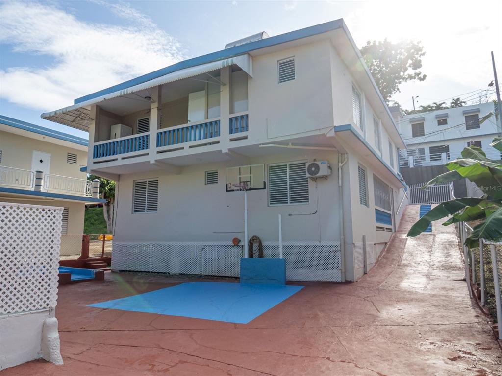 A two-story house features a basketball hoop, a blue painted court, and a concrete driveway — 373 CALLE FRANCISCO COLON GUERRA BO PUEBLO, RINCON, PR
