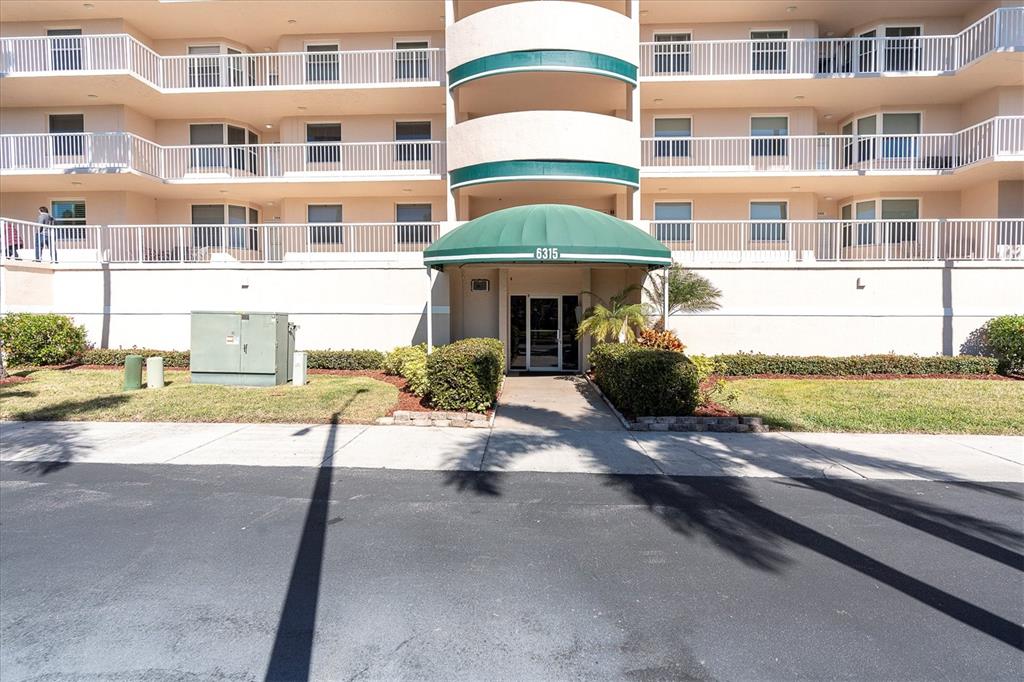 The exterior of a multi-story apartment building features a green awning over the entrance — 6315 SHORELINE DRIVE UNIT 3307, SEMINOLE, FL