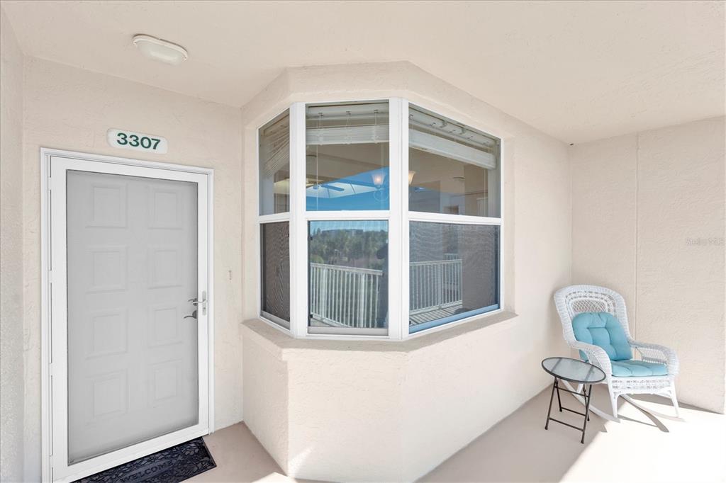 A white front door with a storm door sits next to a bay window — 6315 SHORELINE DRIVE UNIT 3307, SEMINOLE, FL