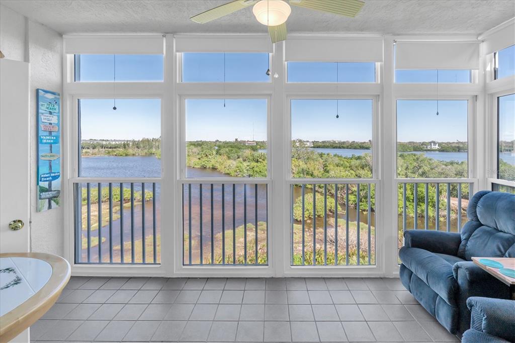 A sunroom with tile flooring, a blue recliner, and large windows overlooking a scenic waterway — 6315 SHORELINE DRIVE UNIT 3307, SEMINOLE, FL
