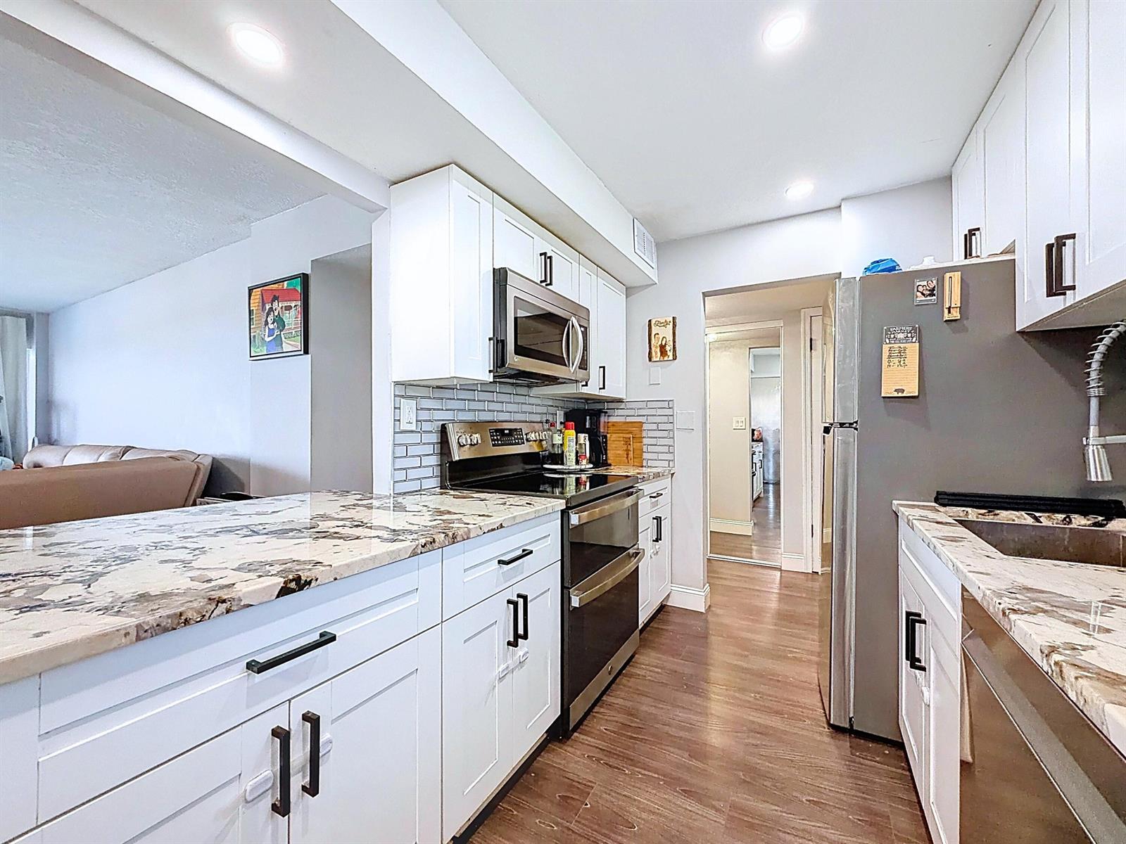 A kitchen features white cabinets, granite countertops, stainless steel appliances, and a subway tile backsplash — 801 S Federal Highway # 816, Pompano Beach FL 33062, POMPANO BEACH, FL