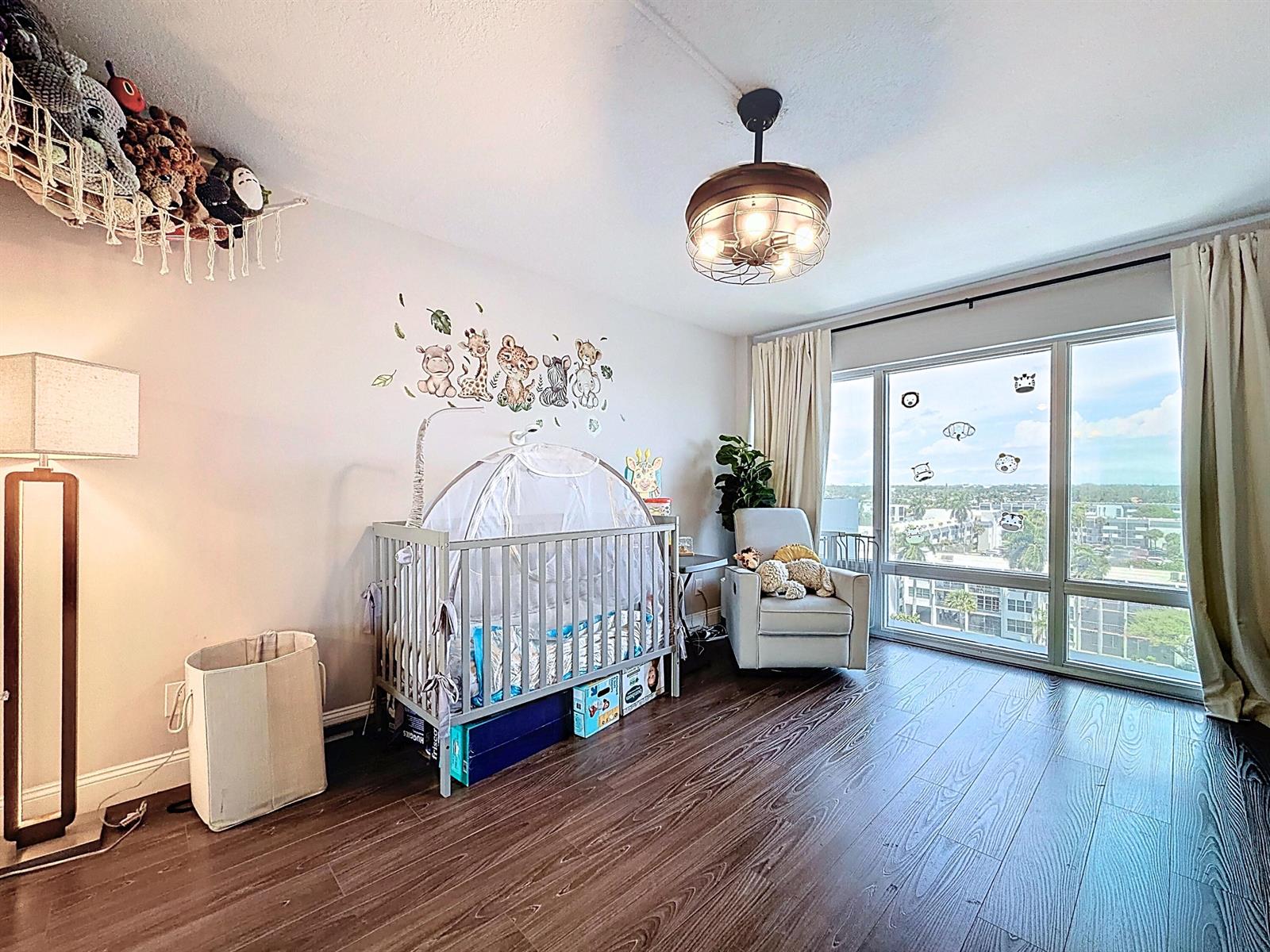 A nursery features a crib, a rocking chair, a ceiling fan, and large floor-to-ceiling windows — 801 S Federal Highway # 816, Pompano Beach FL 33062, POMPANO BEACH, FL