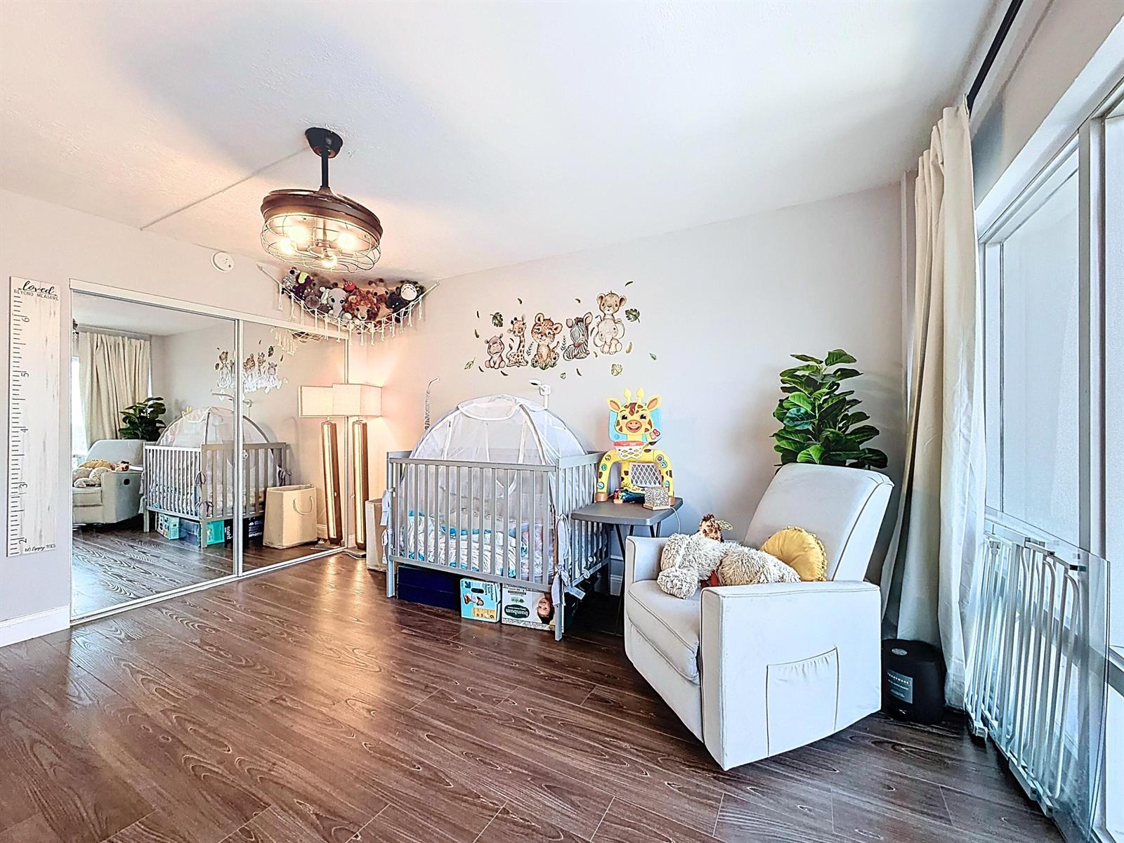 A nursery with wood-look flooring, a crib, a rocking chair, and a mirrored closet — 801 S Federal Highway # 816, Pompano Beach FL 33062, POMPANO BEACH, FL