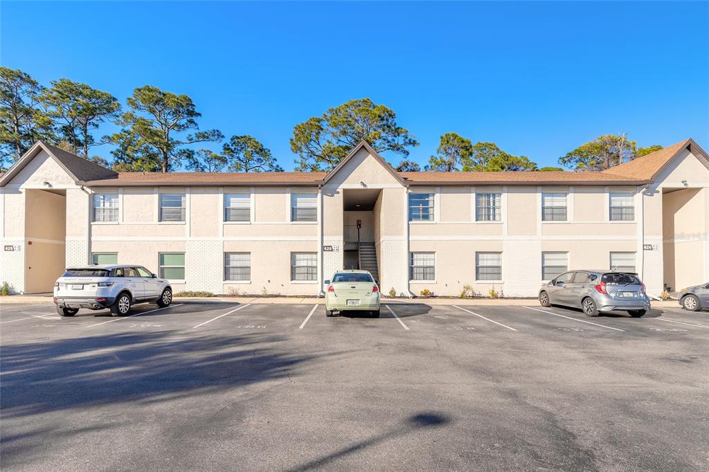A two-story apartment building with a parking lot in front under a clear blue sky — 426 BANANA CAY DRIVE UNIT I, SOUTH DAYTONA, FL