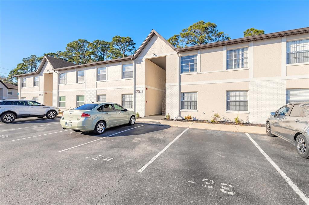 A two-story apartment building exterior features a parking lot with several parked cars — 426 BANANA CAY DRIVE UNIT I, SOUTH DAYTONA, FL