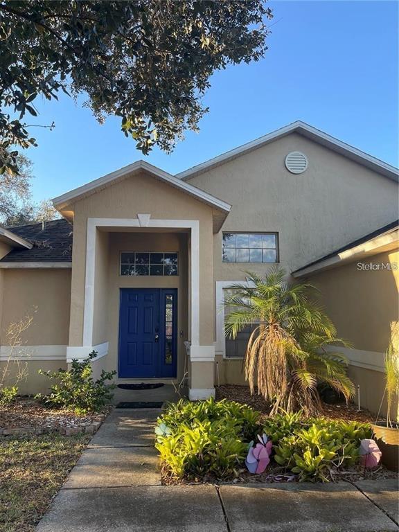 A tan house exterior features a blue front door, a palm tree, and landscaping — 519 THOUSAND OAKS BOULEVARD, DAVENPORT, FL