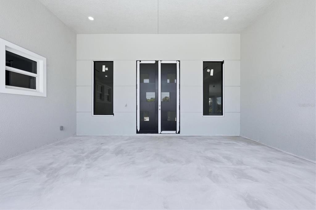 A covered patio features a light gray floor, white walls, and a double glass door — 9232 ARRID CIRCLE, PORT CHARLOTTE, FL