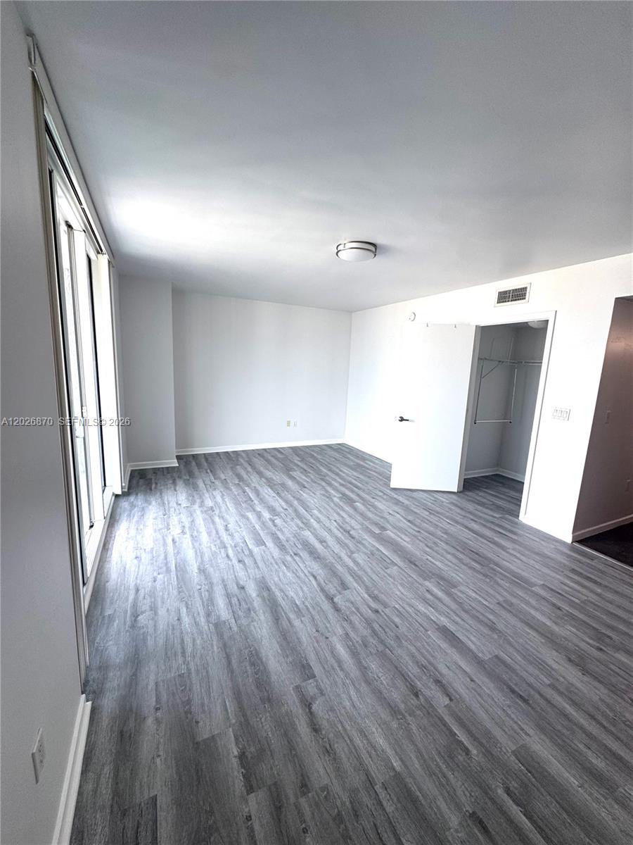 This studio apartment features gray wood-look flooring, a small kitchenette, and a walk-in closet — 50 Biscayne Blvd # 3303, Miami FL 33132, MIAMI, FL