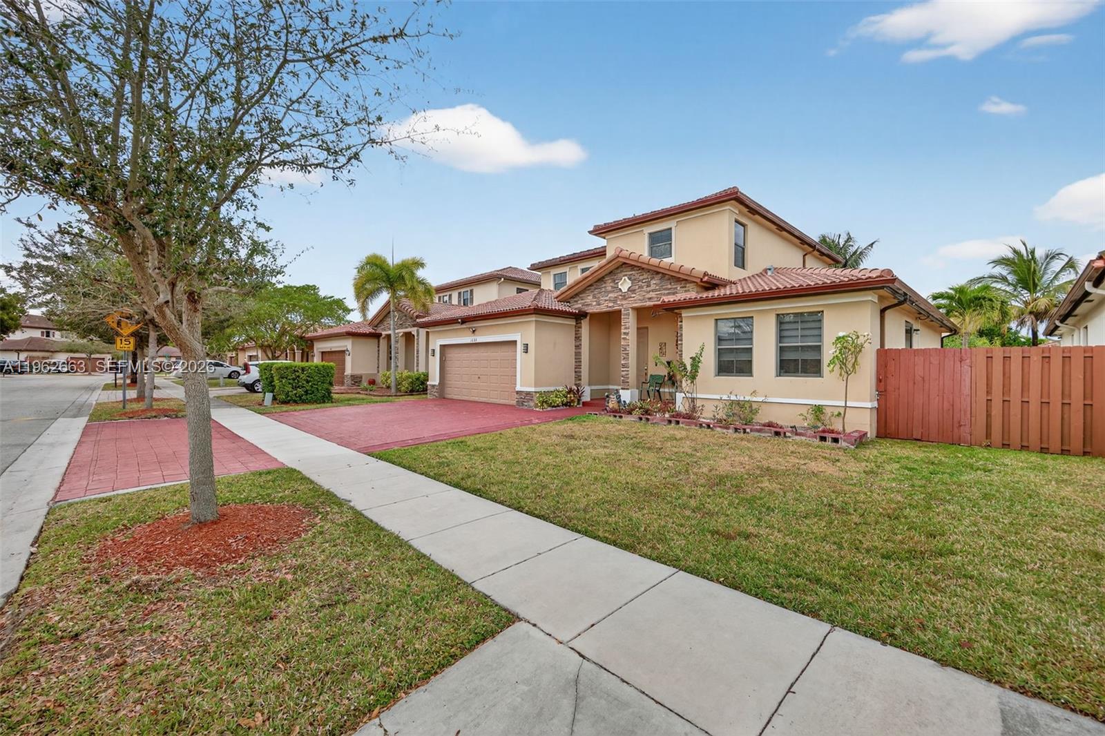 A two-story suburban house with a red tile roof, tan stucco exterior, and attached garage — 3669 SE 2nd Ct, Homestead FL 33033, HOMESTEAD, FL