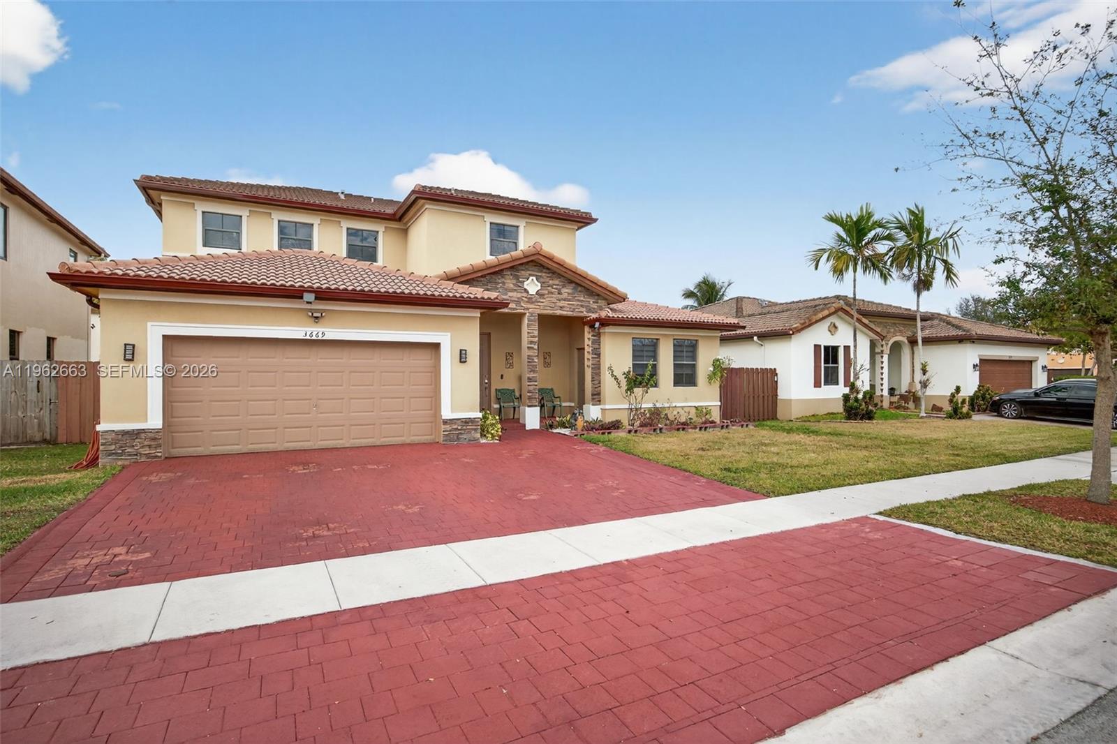 A two-story house with a red brick driveway and a tiled roof under a blue sky — 3669 SE 2nd Ct, Homestead FL 33033, HOMESTEAD, FL