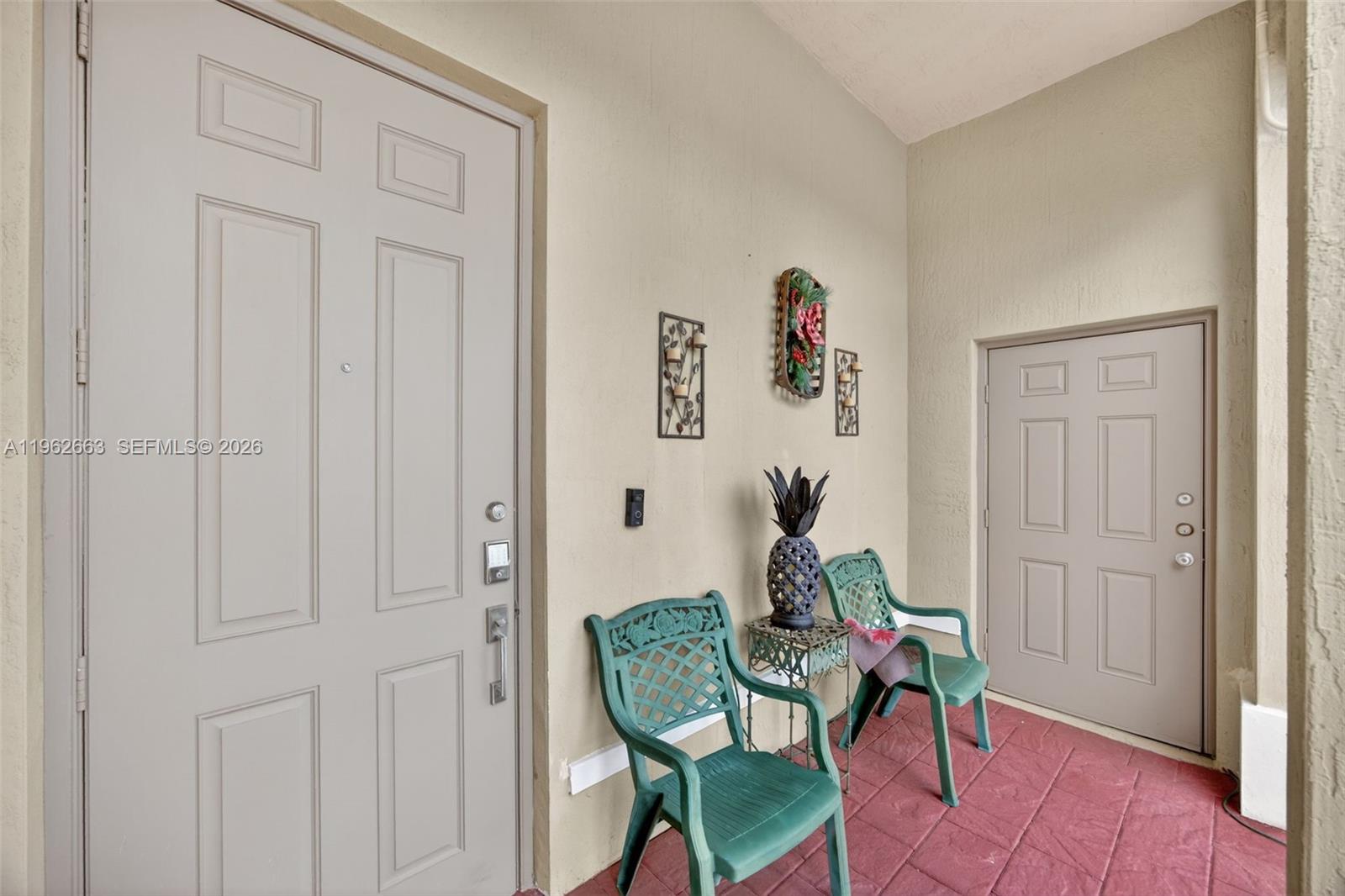 A covered entryway features two green chairs, a small table, and two beige doors — 3669 SE 2nd Ct, Homestead FL 33033, HOMESTEAD, FL