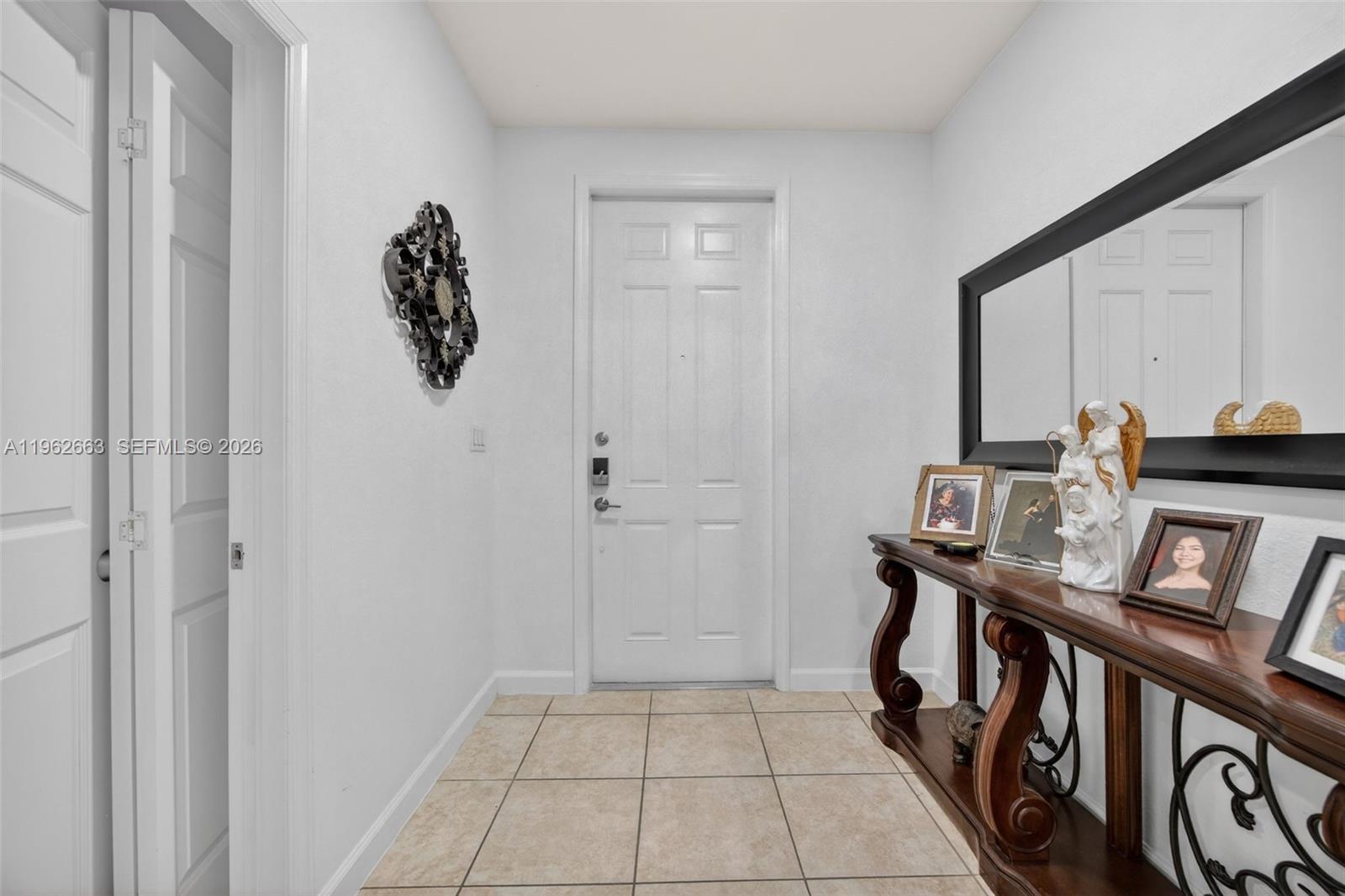 An entryway features a tiled floor, a white front door, and a wooden console table — 3669 SE 2nd Ct, Homestead FL 33033, HOMESTEAD, FL